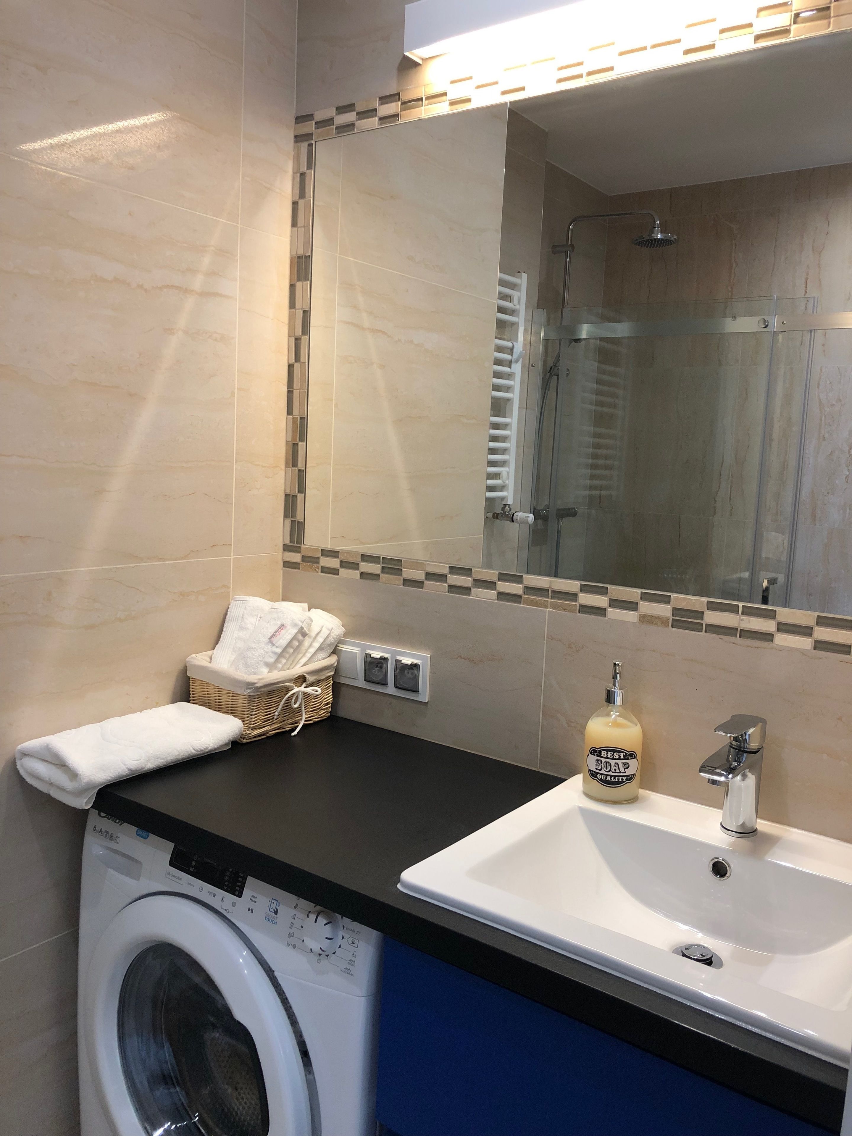 Un baño moderno con lavadora, lavabo y cabina de ducha de vidrio.