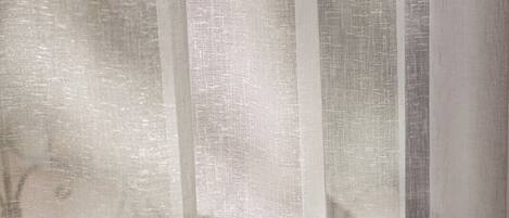 A window with sheer curtains featuring a subtle pattern.