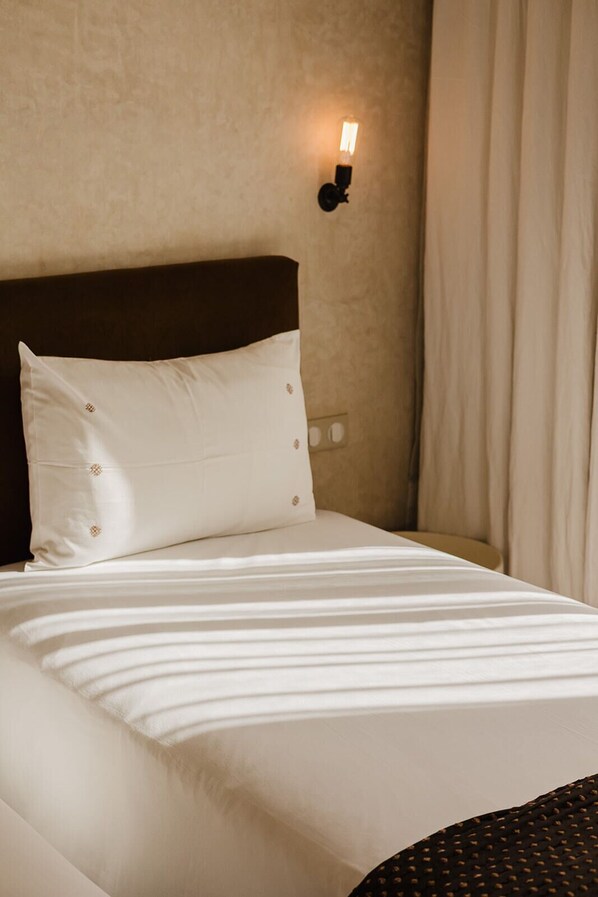 A neatly made bed with white bedding and a dark headboard.