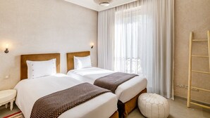 A hotel room with two beds, a chandelier, a large window with curtains, a bedside table, and a wooden ladder. - Villa de Luxe Domaine des Kasbahs C5 (Marrakech)