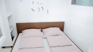 A small, neatly made bed with a wooden headboard, two pillows, and a light-colored bedspread. - B Apartment (Ljubljana)