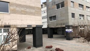 A modern building with a courtyard featuring potted plants and a signboard. - B Apartment (Ljubljana)