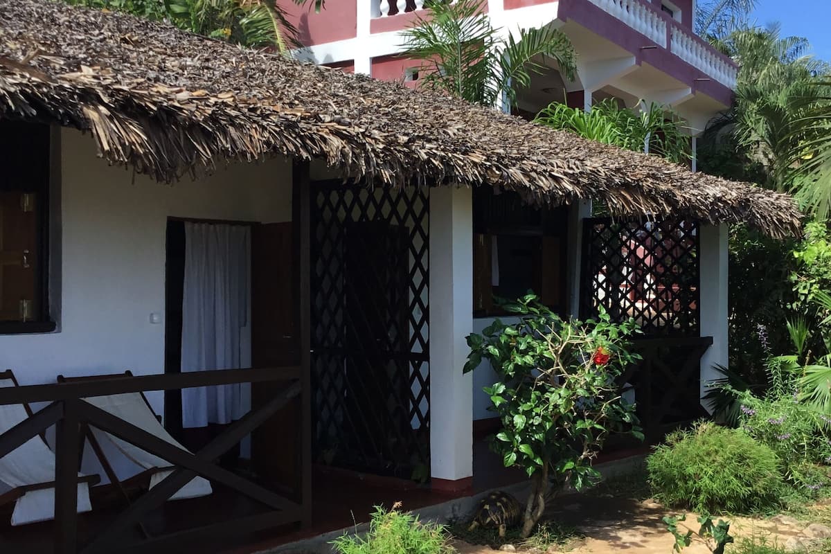 A two-story building with a thatched-roof structure in front.
