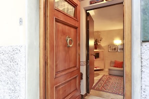 Enter a cozy space with a patterned rug and a shelf with a vase and picture frame.