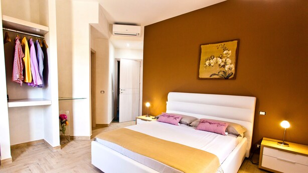 A bedroom with a large bed, bedside tables, a wardrobe, and a painting on the wall. - B&B Shining (Avola)