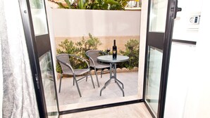 A glass-enclosed balcony with a table and two chairs, a bottle of wine, and a refrigerator. - B&B Shining (Avola)