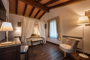 Un dormitorio con una cama con dosel, lámparas de noche, una silla y una mesita de noche.