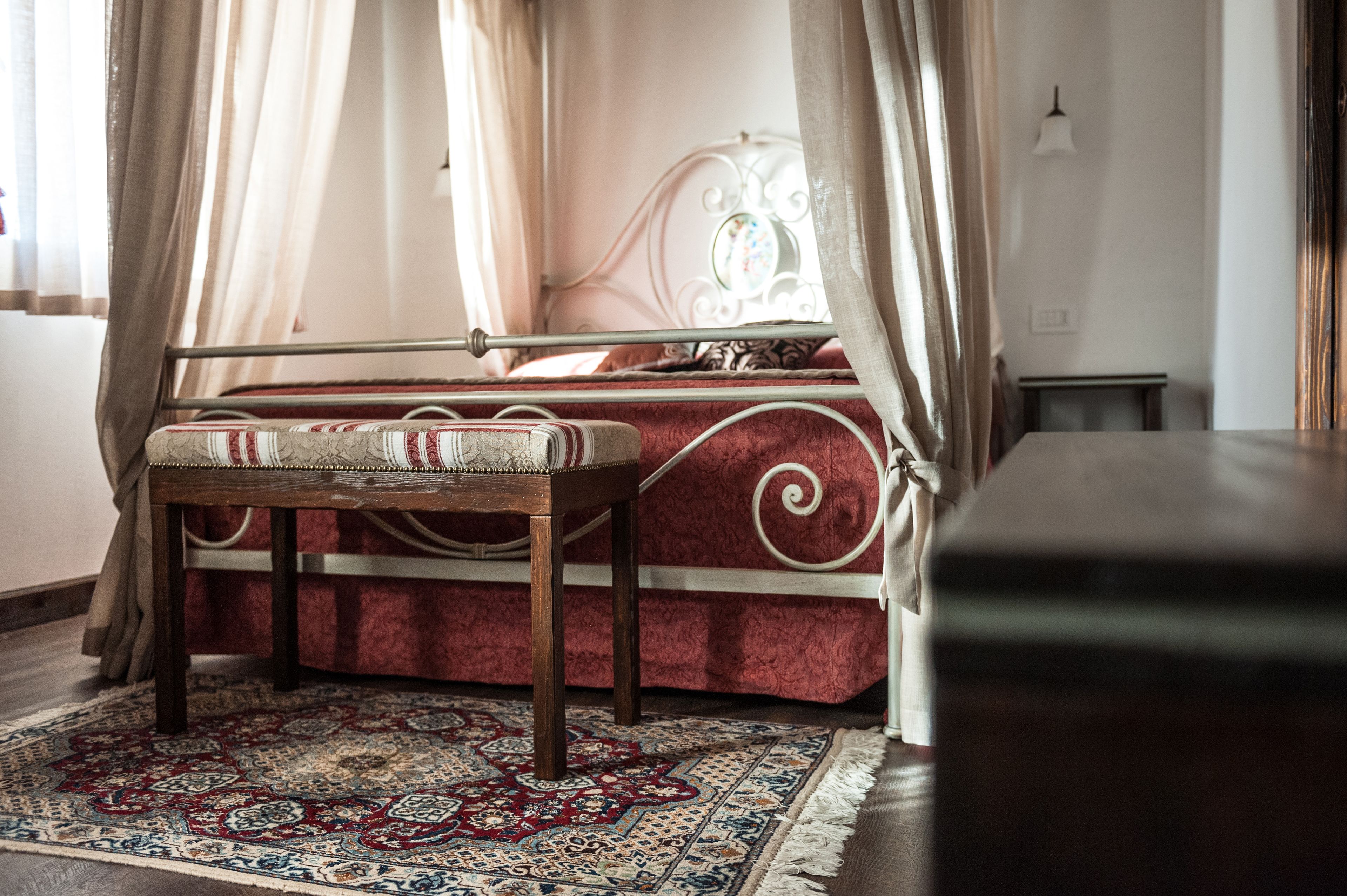 A bedroom with a bed, a bench, a small table, and a rug.