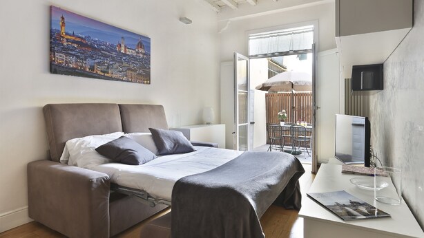 Un dormitorio moderno con una cama, un escritorio y un cuadro de un paisaje urbano.