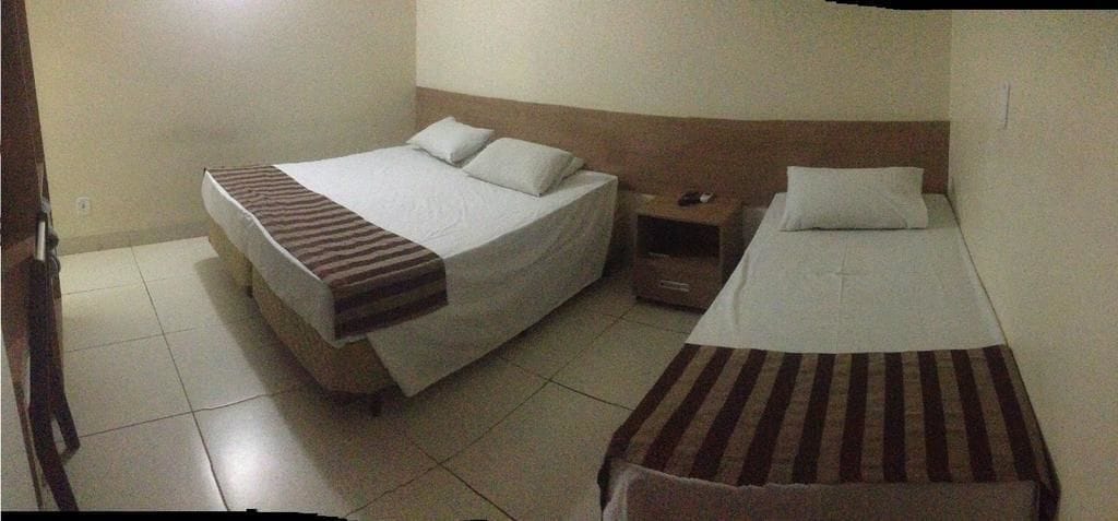 Una habitación de hotel con dos camas individuales, una mesita de noche con lámpara y una pequeña mesa.