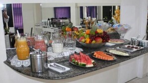 A buffet setup with various fruits, vegetables, and beverages. - Hotel Express (Varzea Grande)