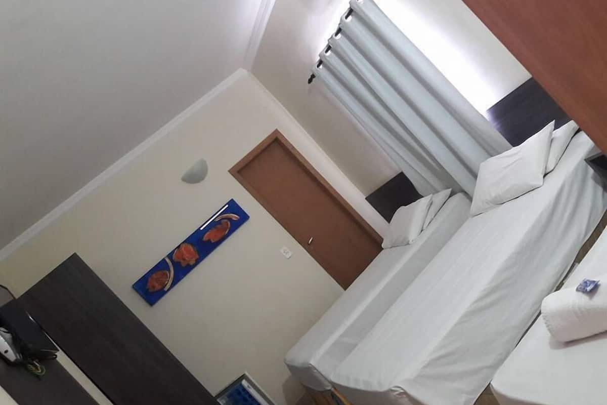 A hotel room with a bed, a small table, a door, and a wall-mounted artwork.