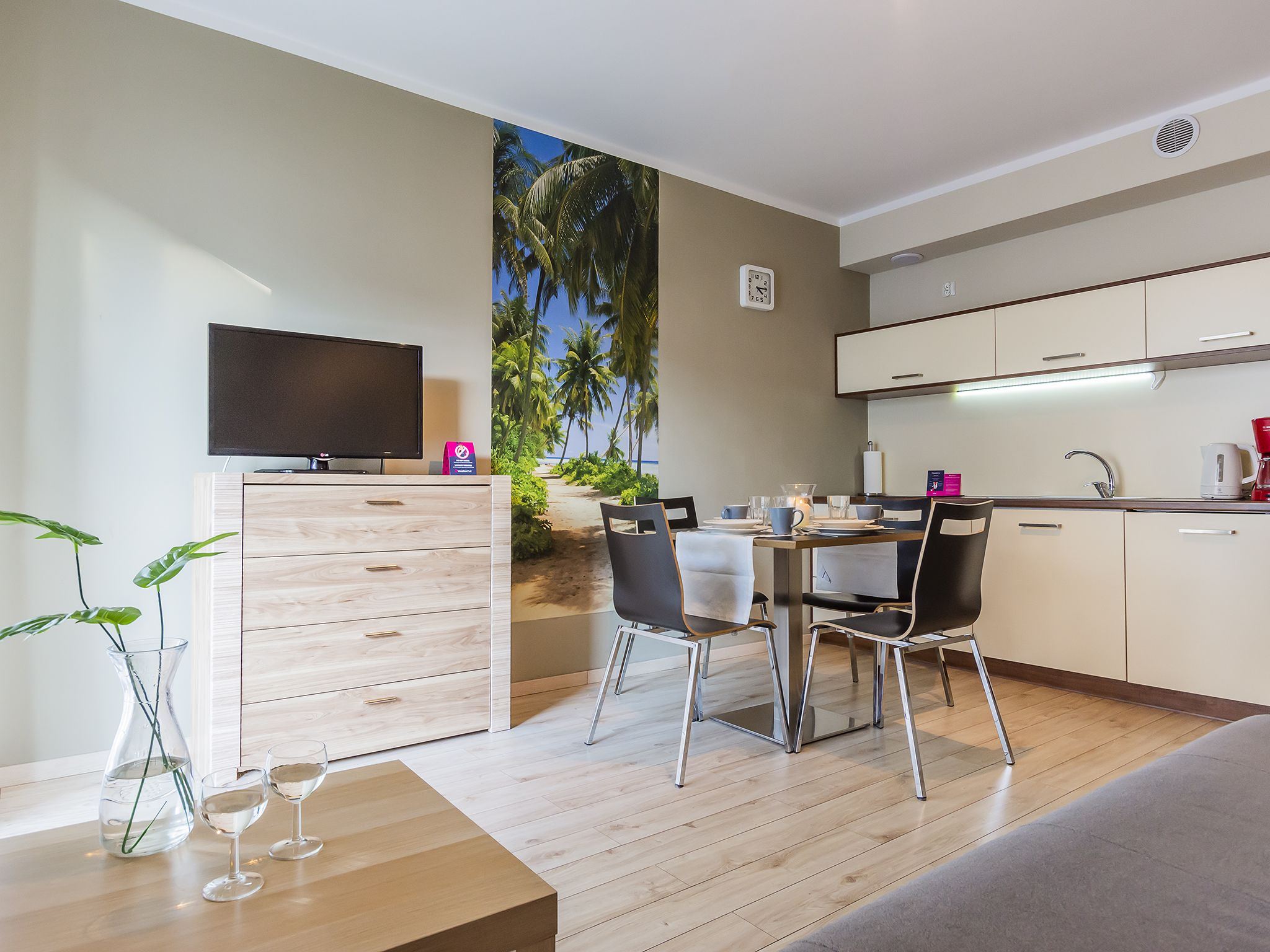 Una cucina moderna con zona pranzo, televisione a schermo piatto e vista sulle palme.