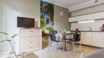 Una cocina moderna con comedor, televisor de pantalla plana y vista a palmeras.