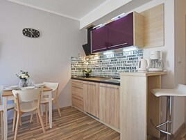 Una cocina moderna con armarios de madera, un reloj negro y una cafetera.