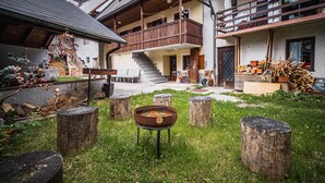 A rustic outdoor area with a wooden deck, a metal fire pit, and a staircase leading to a balcony. - Apartments Wanderlust (Bovec)