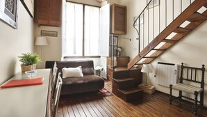 A cozy living room with a brown sofa, a red table, and a wooden staircase. - Lambertesca il Cuore di Firenze (Florence)