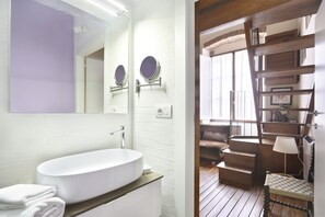 A modern bathroom with a white sink, two round mirrors, and a wooden staircase leading to a living area. - Lambertesca il Cuore di Firenze (Florence)