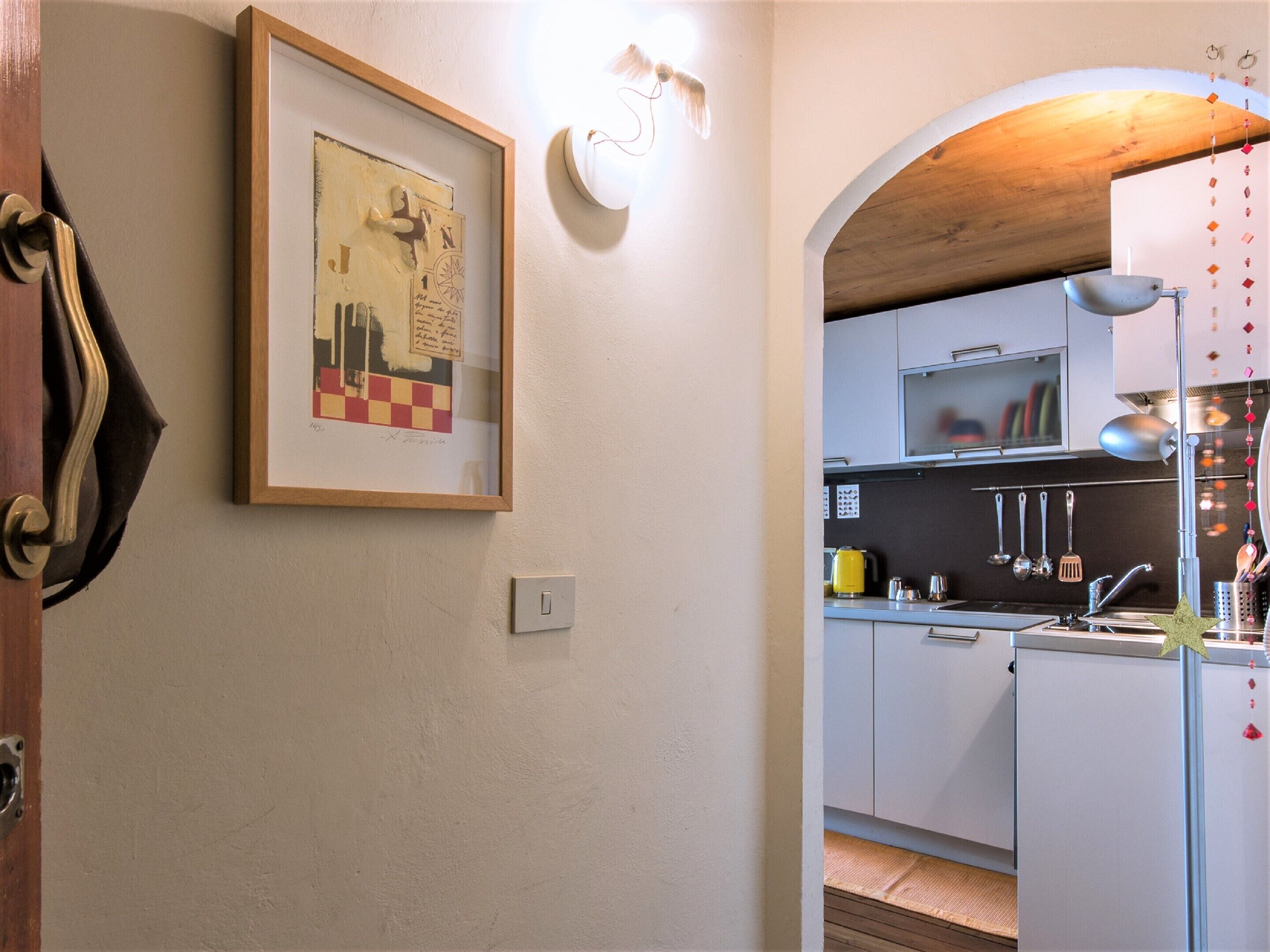 A kitchen with white cabinets, a yellow kettle, and hanging utensils.