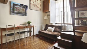 A cozy living room with a brown sofa, a dining table with chairs, and a large window with blinds. - Lambertesca il Cuore di Firenze (Florence)