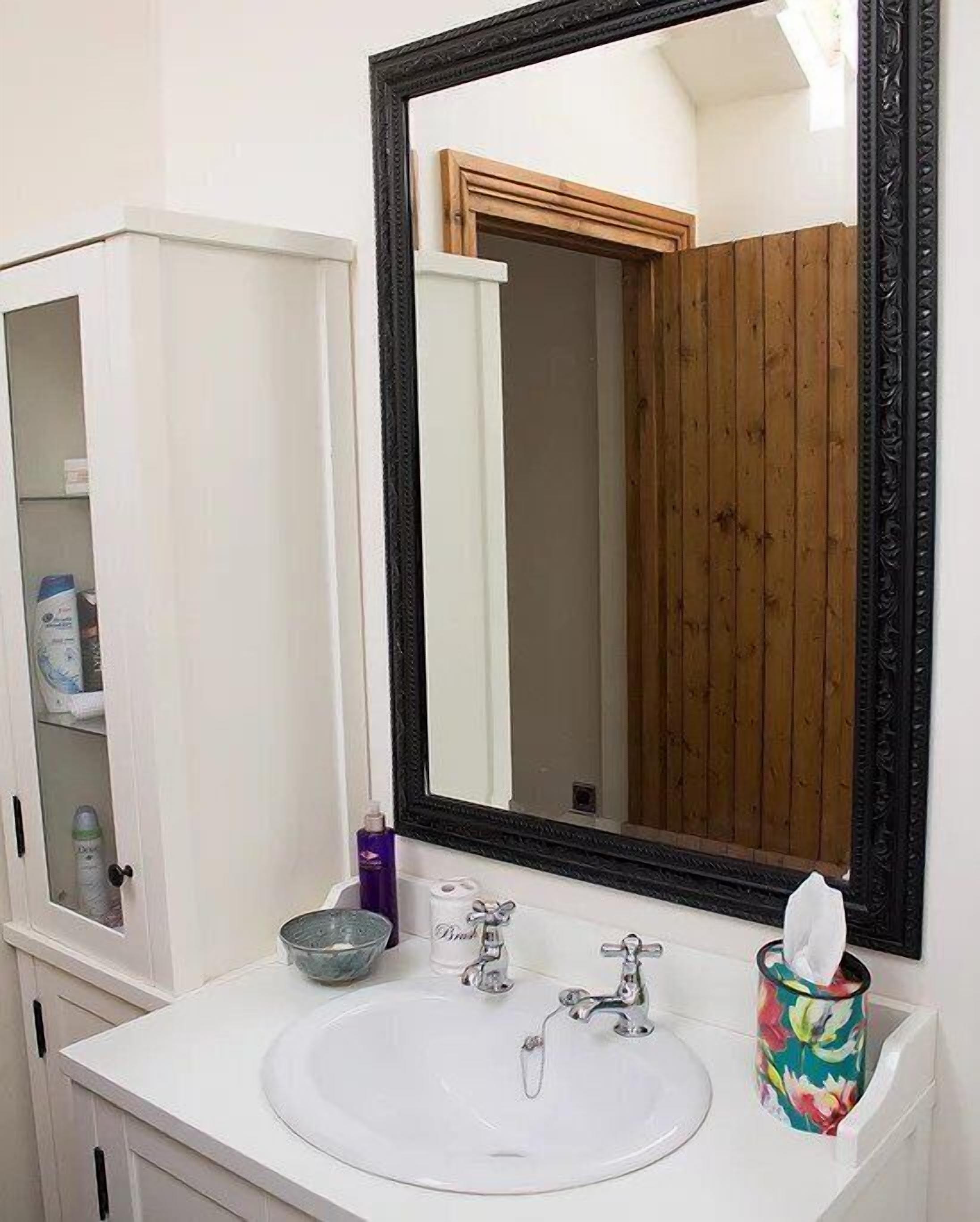 A bathroom with a white sink, a large mirror, and a wooden door.
