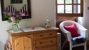 Una habitación acogedora con un aparador de madera, una silla de mimbre y un ventanal grande.