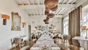 A dining area with long tables, chairs, and a ceiling with exposed beams. - Hôtel Joyet de Maubec (Uzerche)