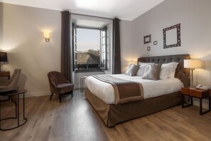 Habitación de hotel con una cama grande, una silla, un escritorio y una ventana con cortinas.