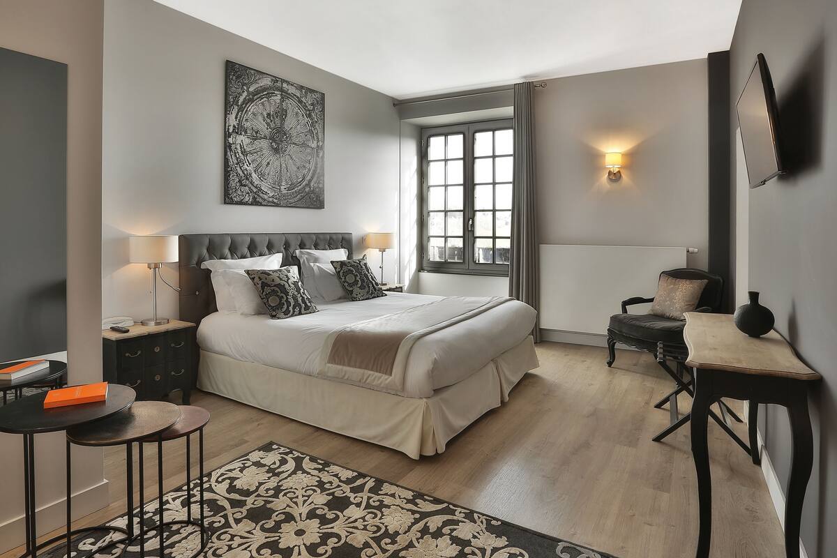 Een moderne slaapkamer met een groot bed, nachtkastjes, een bureau en een raam met uitzicht.
