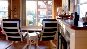 A cabin with two rocking chairs, a small table, and a window with a view of buildings.