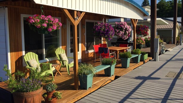 A wooden deck with outdoor seating, a grill, and hanging flower baskets.
