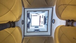 A view from a high ceiling looking down through a square opening, revealing a room with a bed, a window, and a door. - Maggio View (Florence)