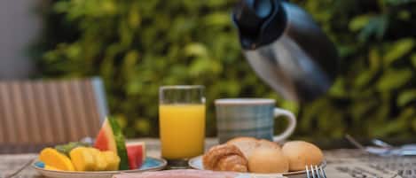 A breakfast table with plates of food, a glass of orange juice, and a coffee pot.
