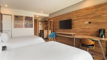 Una habitación de hotel con dos camas, un escritorio, una silla, un televisor y un armario.