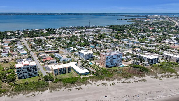 An aerial view of a coastal residential area with beachfront properties, including multi-story buildings and a sandy beach. - RIGHT ON THE BEACH!!  Rockets and Cruise Ships! Kid and pet friendly, 2Br.   (Cocoa Beach)