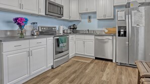 A modern kitchen with white cabinets, stainless steel appliances, and a wooden floor. - RIGHT ON THE BEACH!!  Rockets and Cruise Ships! Kid and pet friendly, 2Br.   (Cocoa Beach)