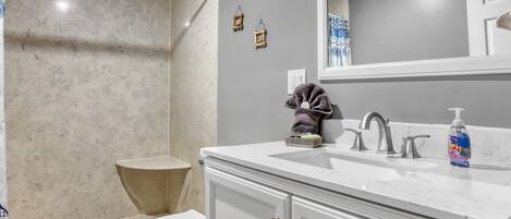 Une salle de bain comprenant des toilettes, un lavabo et un espace douche.