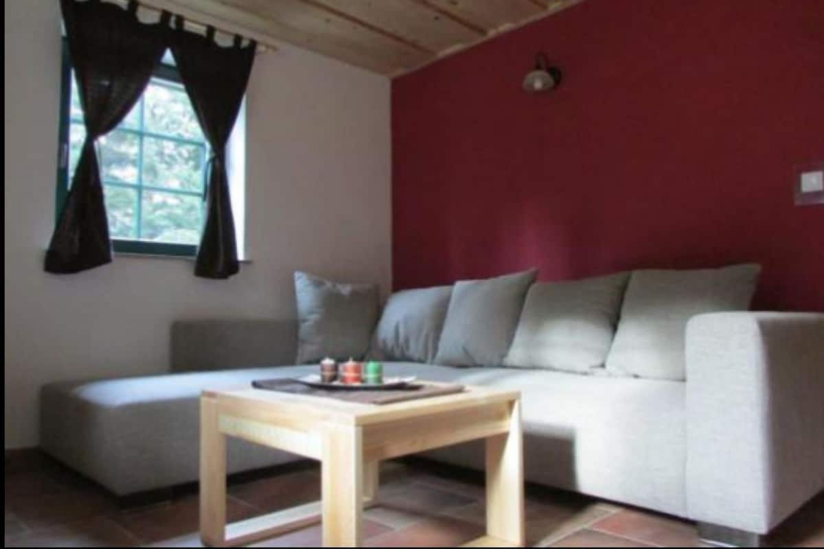 A living room with a sofa, a small wooden table, and a window with curtains.