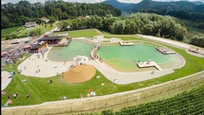 Vista aérea de un parque con varias zonas de natación, una amplia zona de arena y un edificio con techo rojo.