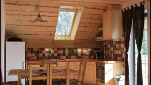 Una cocina compacta con techo de madera, tragaluz, salpicadero de azulejos y servicios básicos como refrigerador, estufa y lavaplatos.