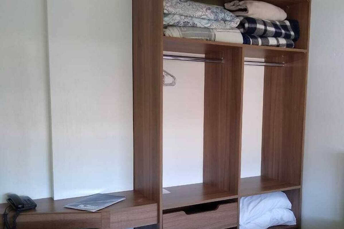 A bedroom with a bed, a desk, a chair, and a wardrobe.