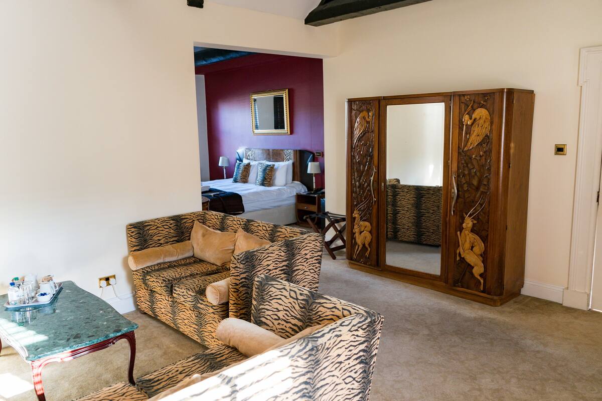 A room with a bed, a tiger-patterned sofa, a wooden wardrobe, and a small table with a tray.