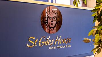 Een receptiebalie met een logo en de naam 'St Giles House Hotel Terrace & Spa'.