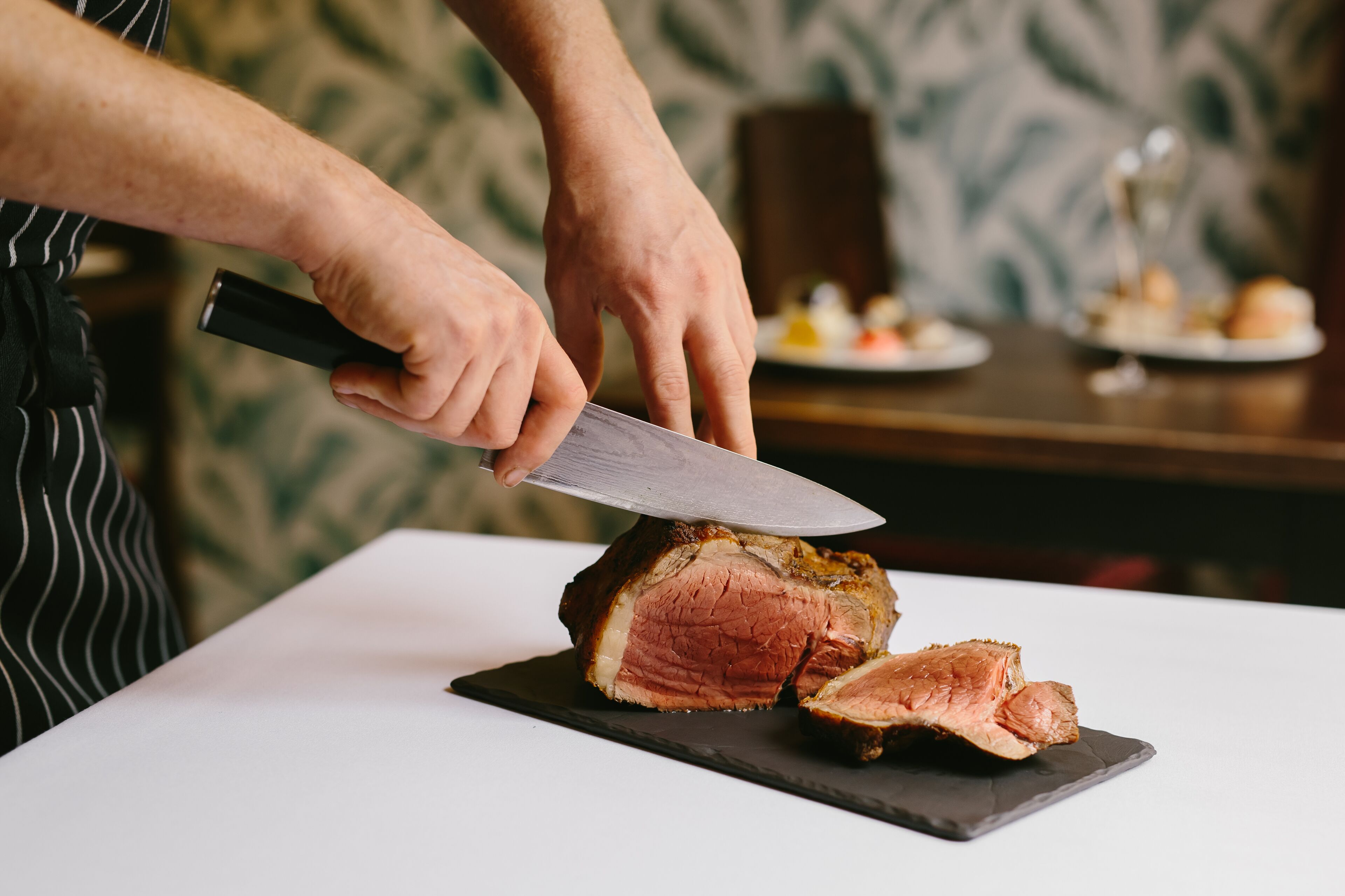 Una persona cortando un trozo grande de carne sobre una tabla.