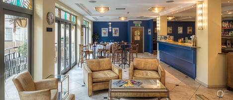 A hotel lobby with a bar area, seating arrangements, and a clock on the wall.