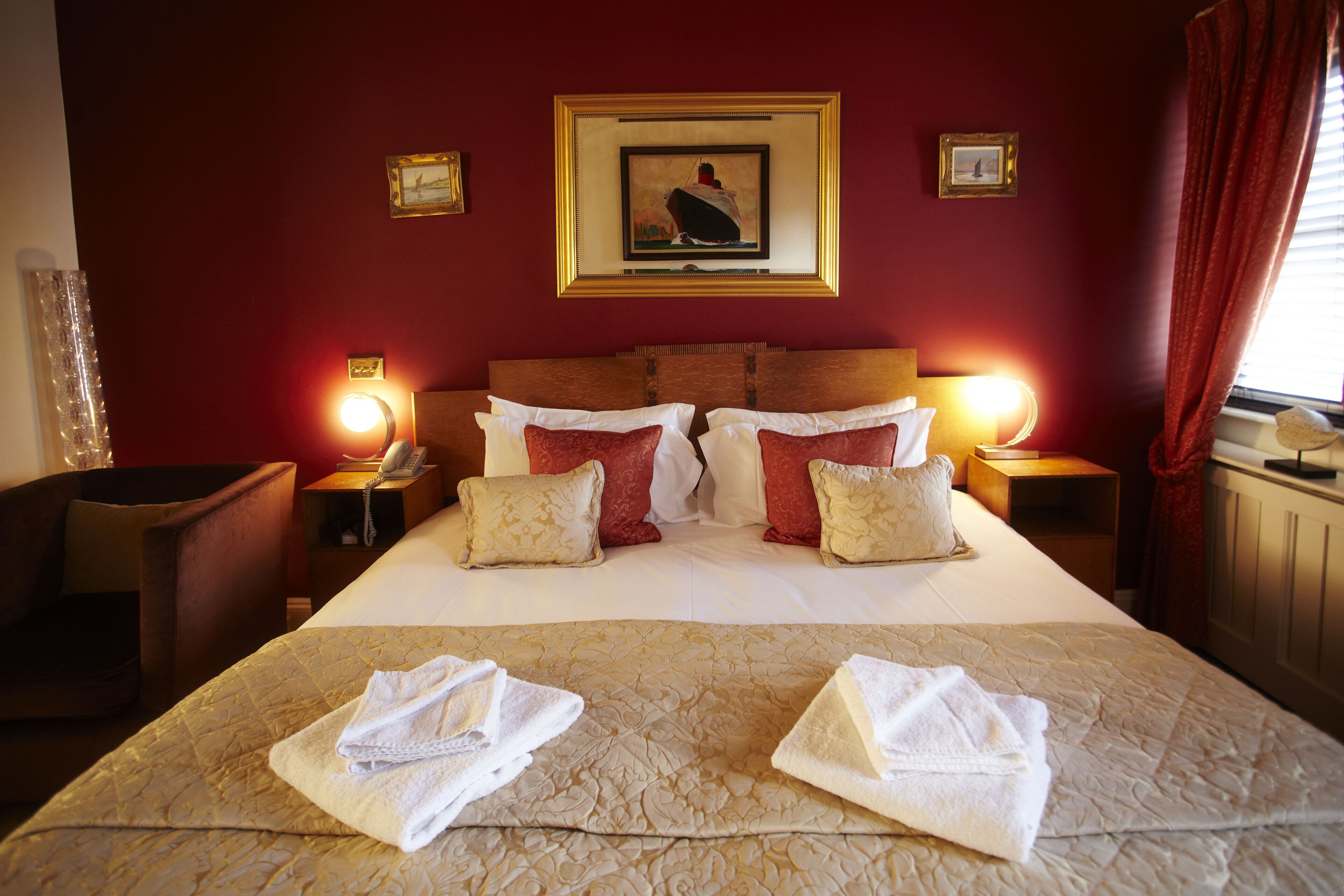 A hotel room with a large bed, two bedside tables, a headboard, and a framed picture on the wall.