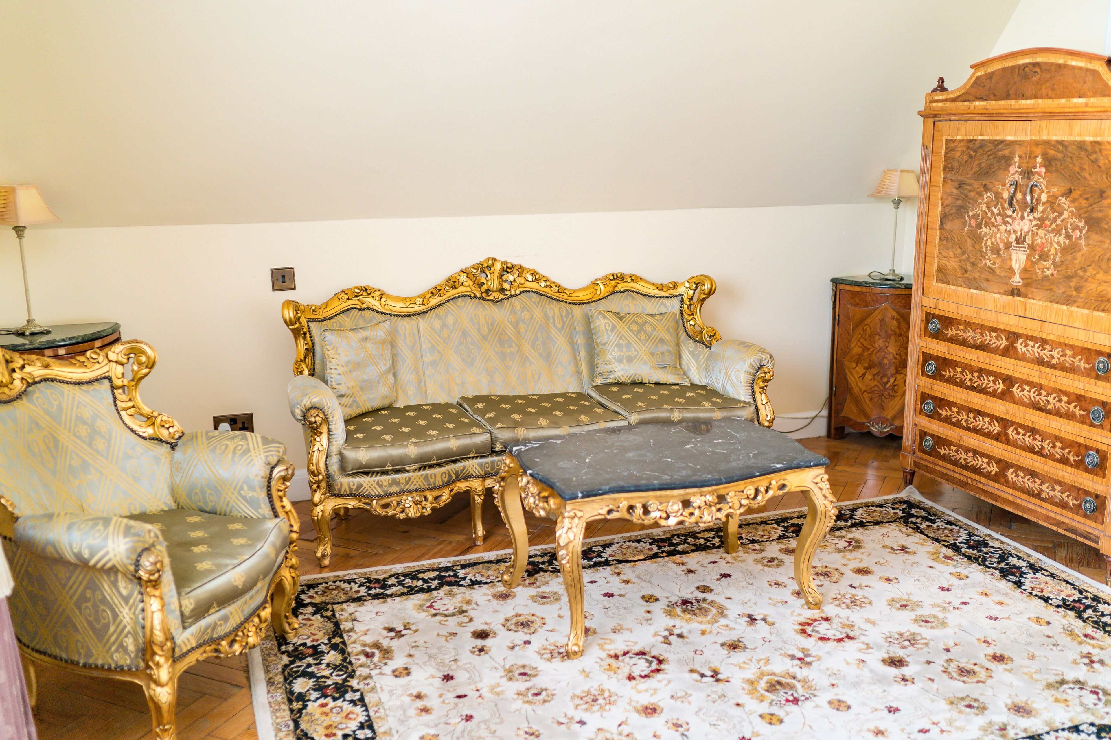 A room with a sofa set, a matching ottoman, and a wooden cabinet.
