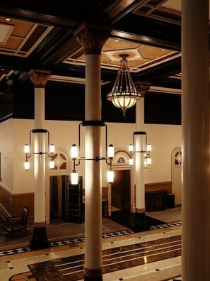 A grand lobby with a chandelier, columns, and a staircase. - The Driskill (Austin)