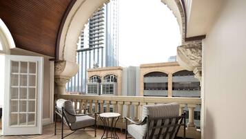 A balcony with two chairs and a small table, overlooking a cityscape with modern buildings.