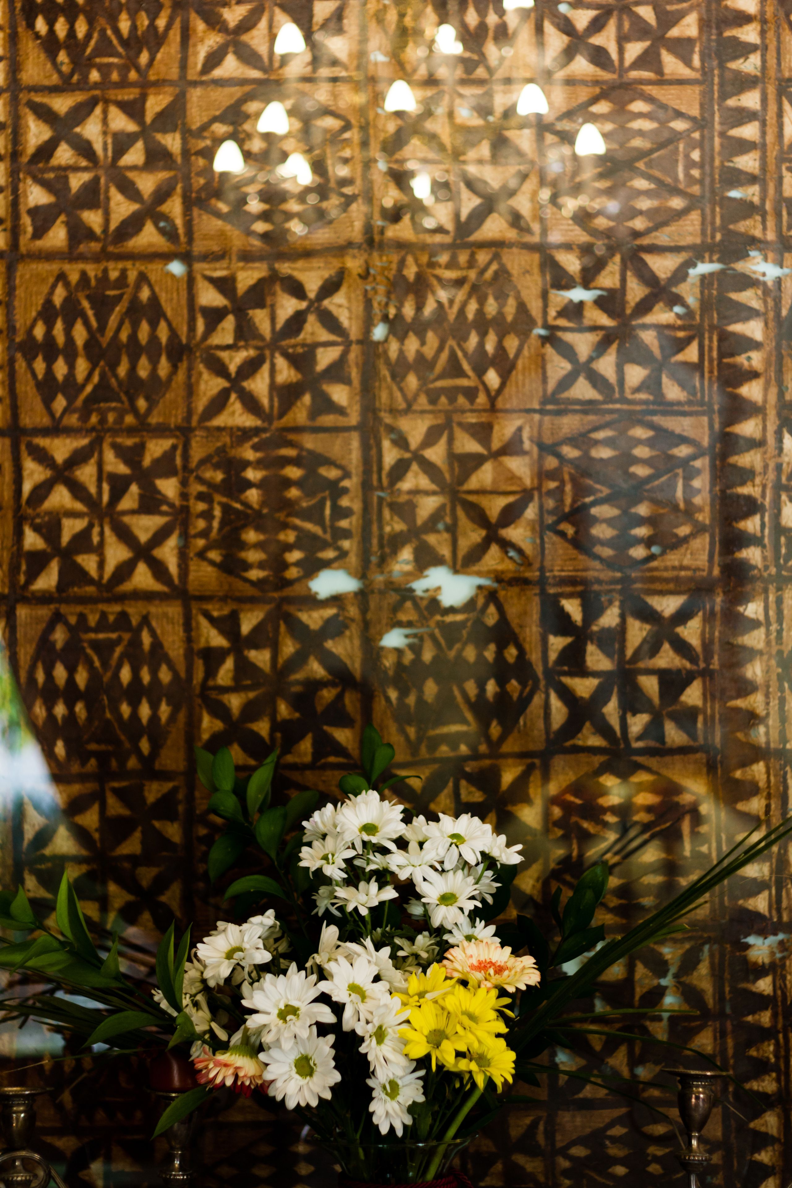 Una pared decorativa con patrones geométricos y un arreglo floral en primer plano.